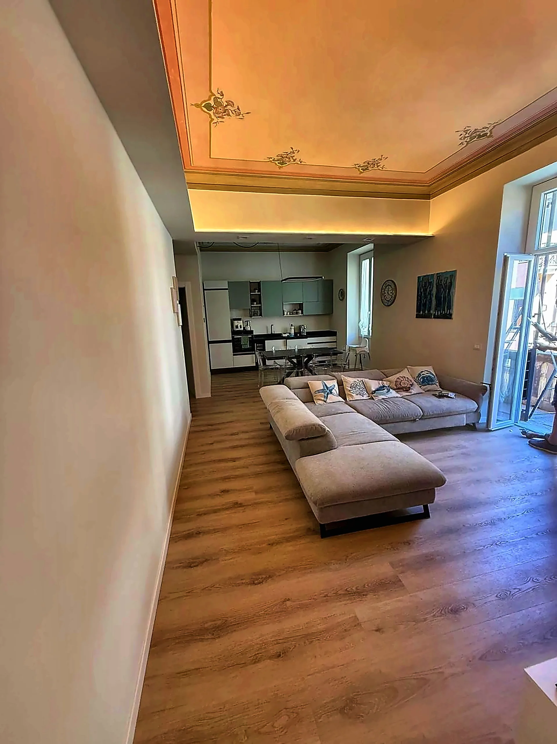 Soggiorno con soffitto decorato e cucina a vista